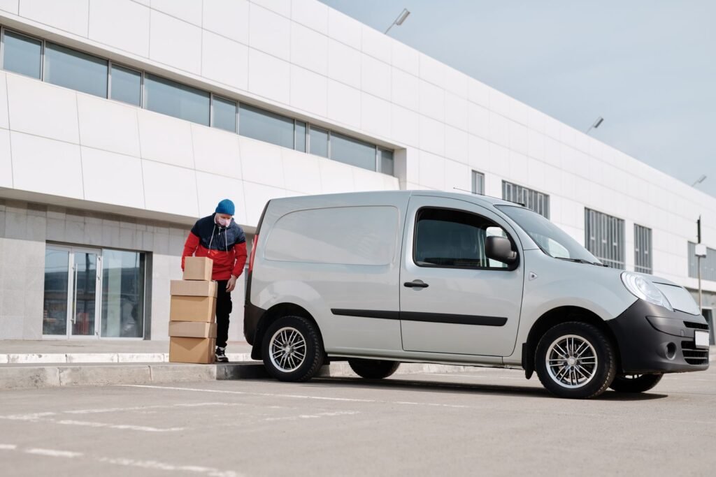 Worker loading cardboard boxes from delivery van outside warehouse - bulk supply distribution Content-Disposition: form-data; name="caption" Worker loading cardboard boxes from delivery van outside warehouse - bulk supply distribution