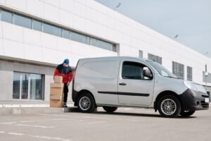 Worker loading cardboard boxes from delivery van outside warehouse - bulk supply distribution Content-Disposition: form-data; name="caption" Worker loading cardboard boxes from delivery van outside warehouse - bulk supply distribution