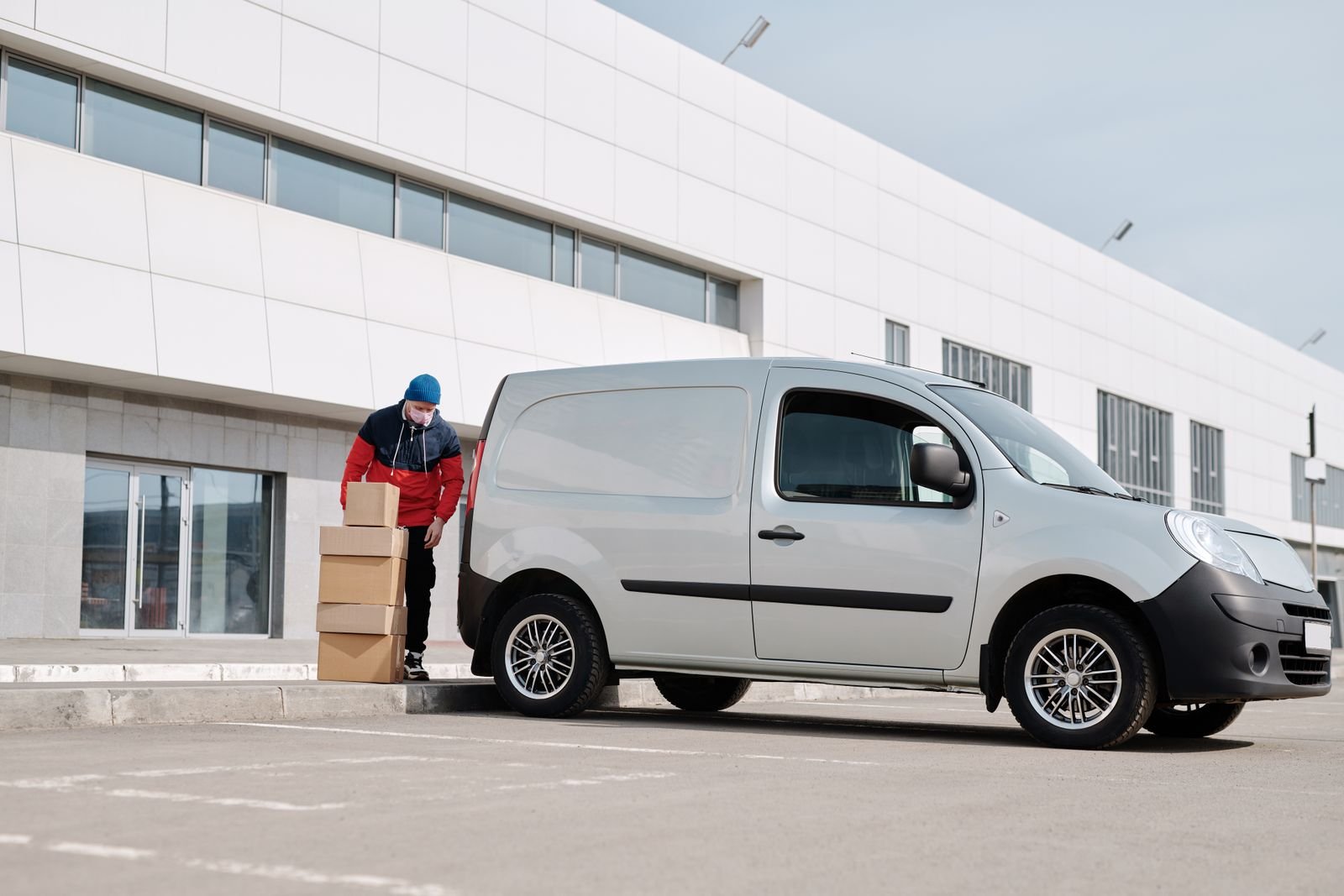 Worker loading cardboard boxes from delivery van outside warehouse - bulk supply distribution Content-Disposition: form-data; name="caption" Worker loading cardboard boxes from delivery van outside warehouse - bulk supply distribution